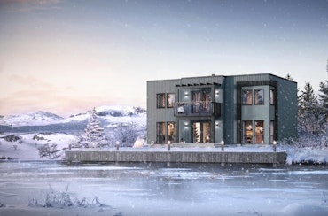 Funkisinsprert, moderne hus i vinterlandskap ved isbelagt vann. Hustypen Himin beiset i blågrå farge, mørke detaljer og store vinduer.