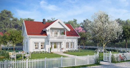 Sjarmerende hvitt hus med rød taksten i koselig hage, med hvitt stakittgjerde rundt. Husmodellen Aprilvår har to etasjer og overbygd terrasse.