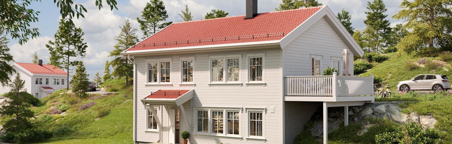 Klassisk hvitmalt hus med rødt tak på skrå tomt. Huset Marsmorgen har stor terrasse med utgang fra hovedplan. Grønn og frodig hage i sommervær.