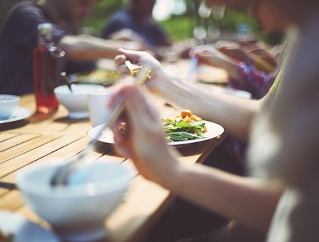 Nærbilde av et middagsbord utendørs der folk sitter og spiser.