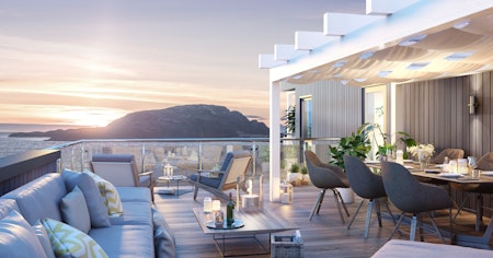 Stor takterrasse med pergola, loungesofa og spisebord- og stoler på husmodellen Lifa. Utsikt mot hav og solnedgang.
