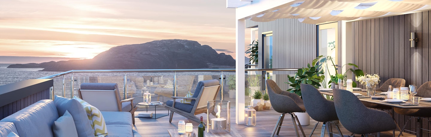 Stor takterrasse med pergola, loungesofa og spisebord- og stoler på husmodellen Lifa. Utsikt mot hav og solnedgang.