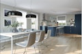 Kjøkken med spisebord i lyst grått og hvit med kjøkkeninnredning i mørk blått med hvit benkeplate. Klassisk husmodell Februarsaga.