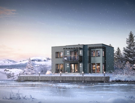 Funkisinsprert, moderne hus i vinterlandskap ved isbelagt vann. Hustypen Himin beiset i blågrå farge, mørke detaljer og store vinduer.