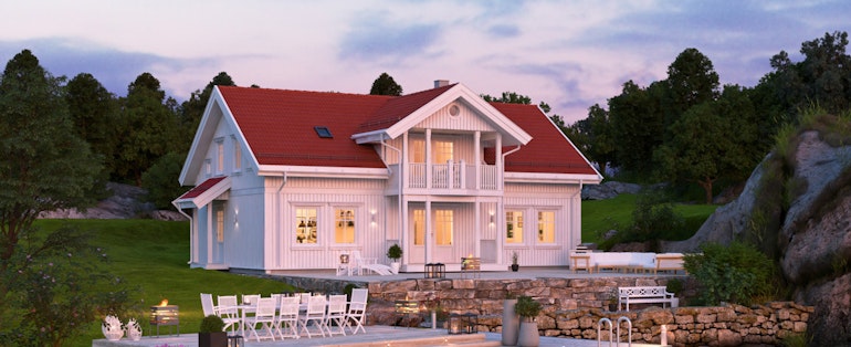 Austegaard er et stilrent, klassisk hus som her vises frem hvitmalt og i nydelig kveldssol, pent plassert ved vannet.
