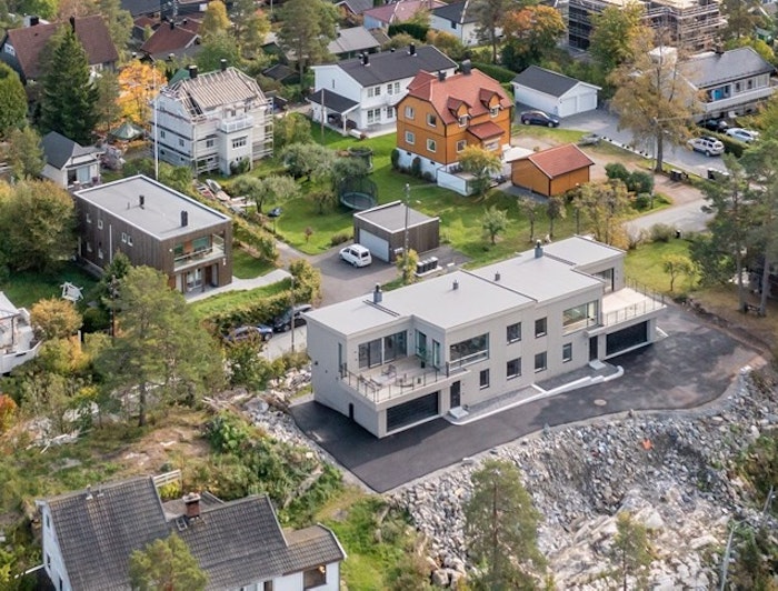 Dronebilde om sommeren over eiendommer på Myrvoll i Oppegård. Med ny 2-mannsbolig fra Skalahus i fokus.