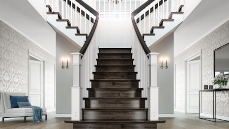 Herskapelig trapp som fører opp til andre etasje i husmodell Constantine. Trappetrinn og håndløper i mørk tre med rekkverk i hvitt.